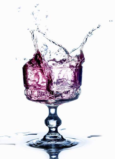 Вид крупным планом фиолетового напитка, брызгающегося из бокала — стоковое фото