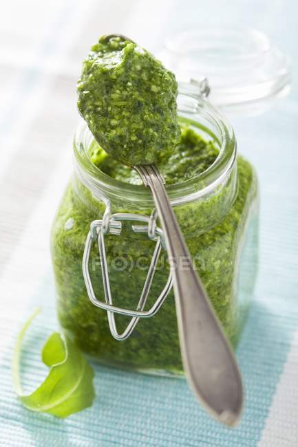 Closeup view of rocket Pesto in a jar and on a spoon — Stock Photo