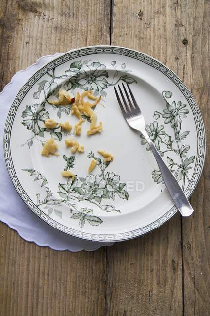 Draufsicht auf einen Teller mit übrig gebliebenen Spätzle-Nudeln und einer Gabel — Stockfoto