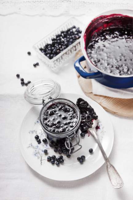 Blueberry jam on spoon and in glass — Stock Photo