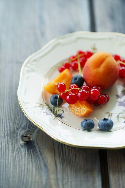 Тарілка з абрикосами і червоною смородиною — стокове фото