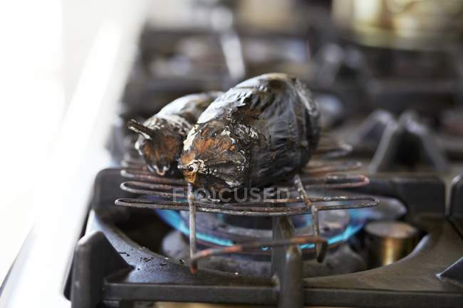 Charred aubergine on a gas stove — Stock Photo