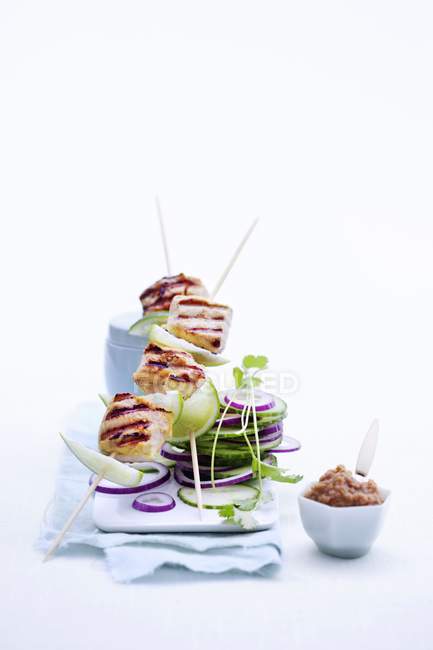 Chicken skewers with cucumber salad on white plate over cloth — Stock Photo