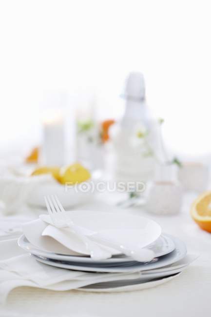 Closeup view of a table laid with piled white plates and cutlery — Stock Photo