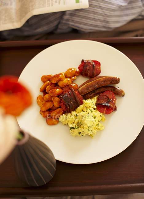 Café da manhã inglês com ovos mexidos, feijão assado, tomate, bacon e salsichas em prato branco — Fotografia de Stock