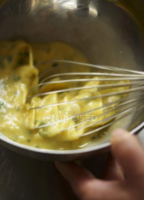 Closeup view of scrambling eggs with a whisk — Stock Photo