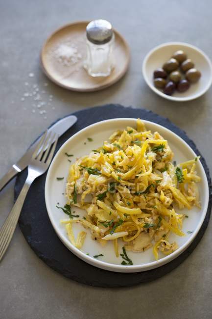 Bacalhau a bras - scrambled eggs with cod and potatoes in white dish — Stock Photo