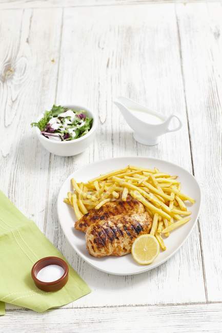 Closeup view of grilled chicken breast with chips and salad — Stock Photo