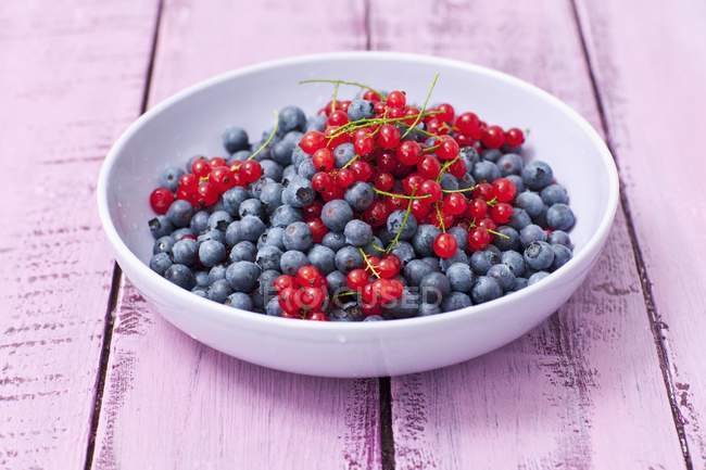 Bowl of redcurrants and blueberries — Stock Photo
