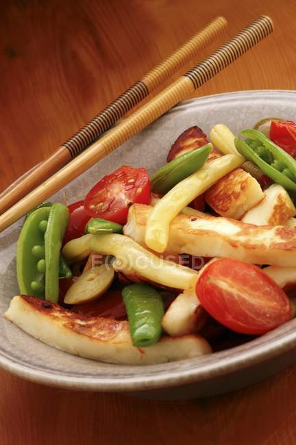 Verduras fritas en un tazón con palillos sobre el plato - foto de stock