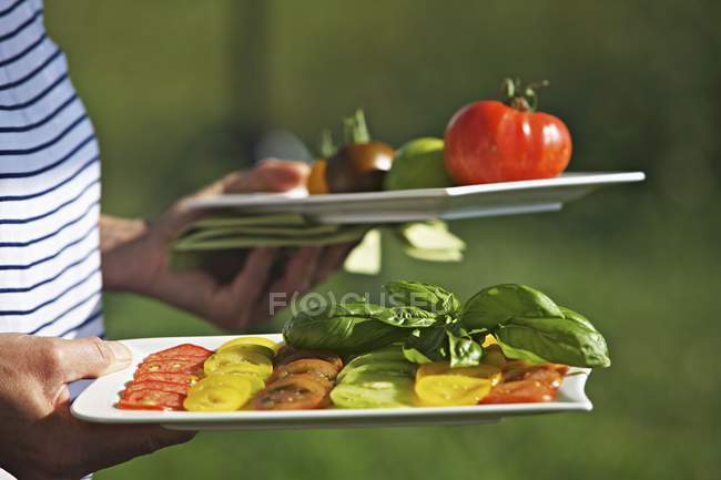 Woman carrying platters of fresh tomatoes — Stock Photo