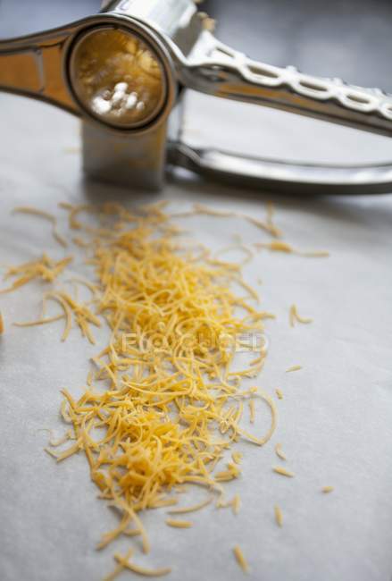 Grated cheddar on white surface — Stock Photo