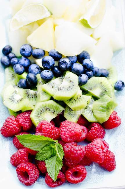 Frutas frescas en rodajas con hojas de menta - foto de stock