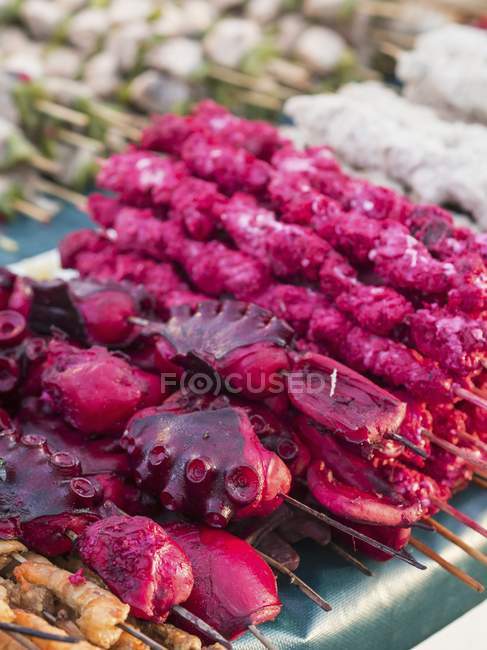 Closeup view of scarlet octopus pieces and other seafood on skewers — Stock Photo