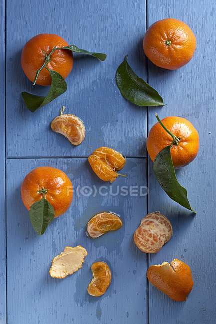 Whole and peeled Clementines with leaves — Stock Photo