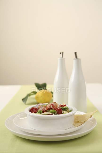 Insalata di fave - bean salad with dried tomatoes and bacon in white bowl — Stock Photo