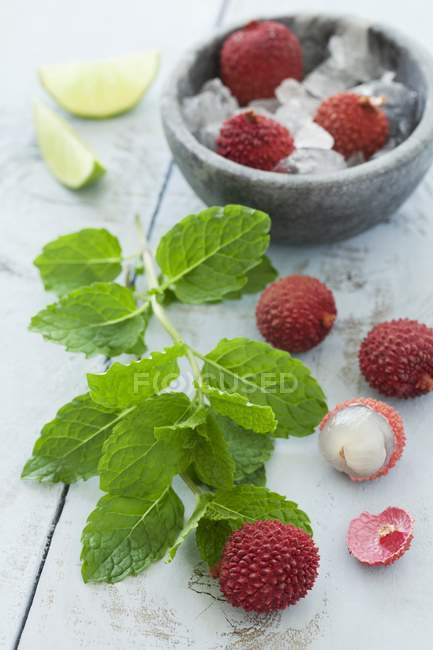 Lychees with mint and lime wedges — Stock Photo