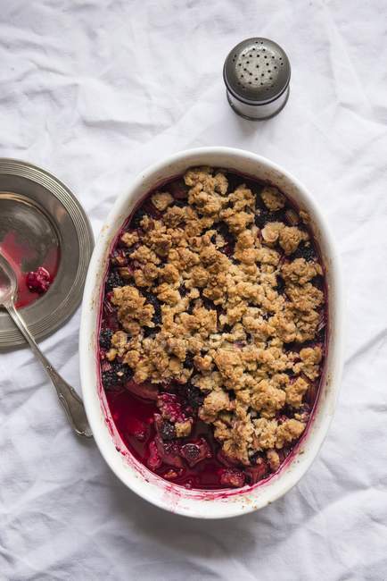 Closeup view of mixed berry Crumble in baking dish with spoon — Stock Photo