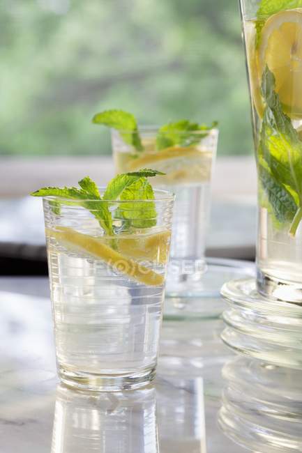 Лимонна вода з м'ятою в двох склянках і глечиком — стокове фото