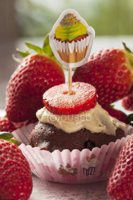 Cupcake with pile of fresh strawberries — Stock Photo