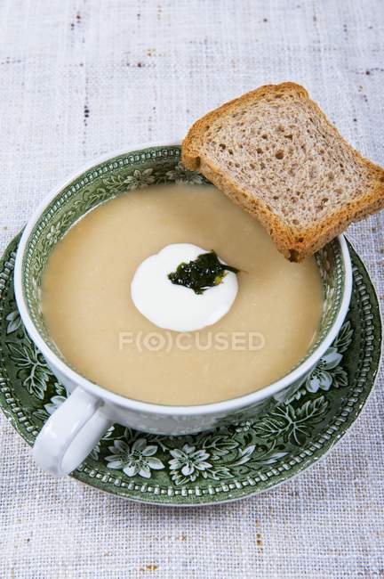 Cream of courgette soup with slice of bread — Stock Photo