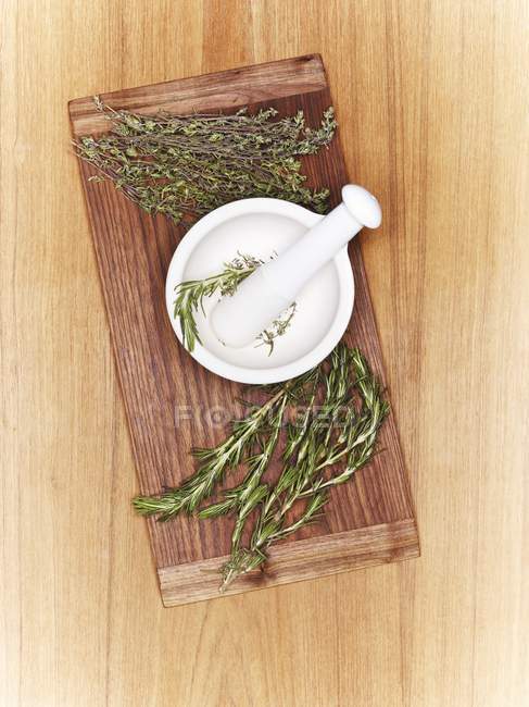 Top view of a mortar with fresh herbs on a wooden board — Stock Photo