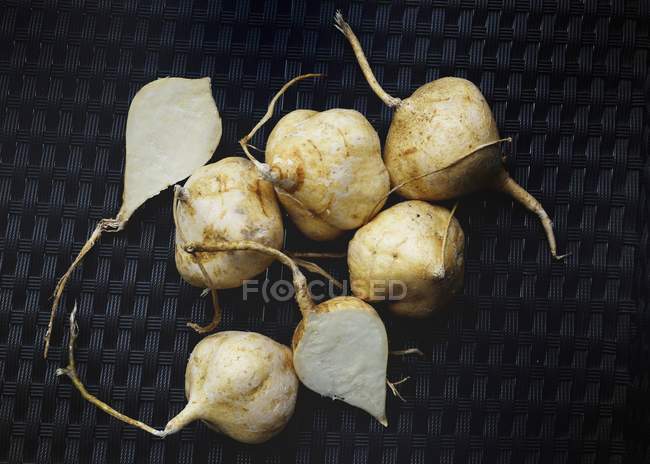 Хикама корнеплоды лежащие на черной поверхности — стоковое фото
