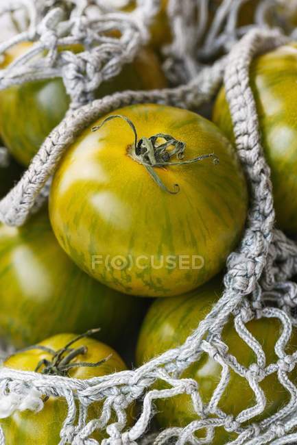 Grüne Tomaten im Einkaufsnetz — Stockfoto