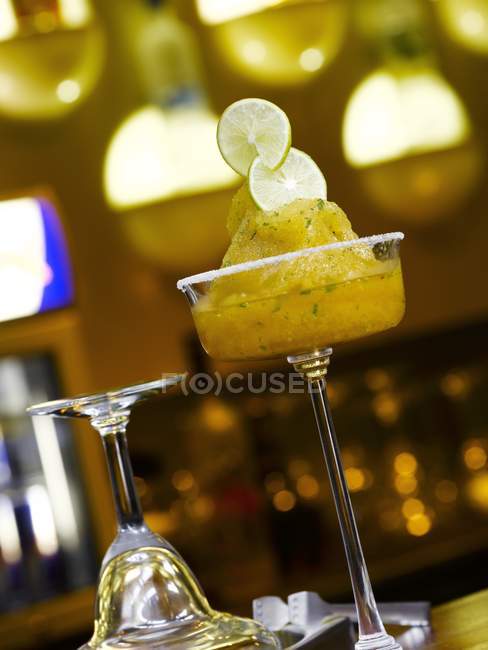 Closeup view of frozen agave cocktail with lime slices in a bar — Stock Photo