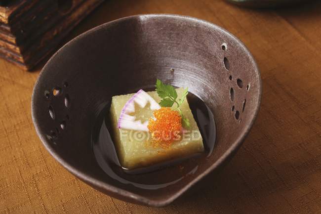 Boiled radish with caviar in brown bowl over wooden surface — Stock Photo