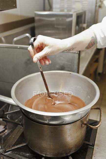 Chef revolviendo chocolate derretido - foto de stock