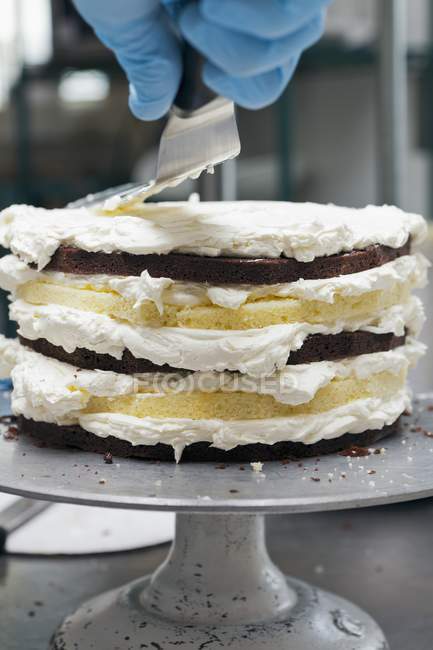 Chef congelando um bolo de camada com cobertura — Fotografia de Stock