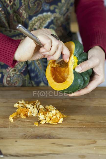 Woman hollowing out acorn squash — Stock Photo