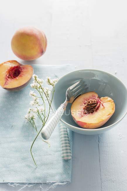 Half of peach in bowl — Stock Photo