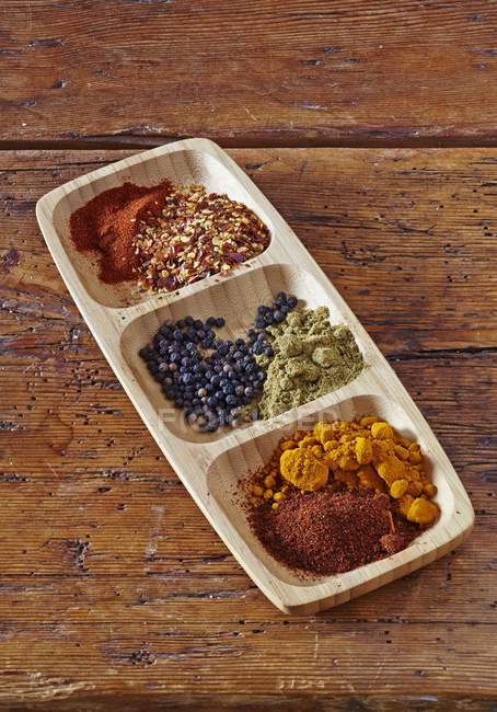 Elevated view of assorted spices in a wooden bowl — Stock Photo