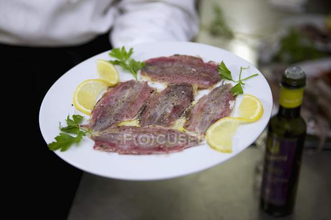 Waiter holding marinated sardines — Stock Photo
