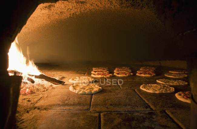 Focaccia in a wood-fired oven with fire flame — Stock Photo