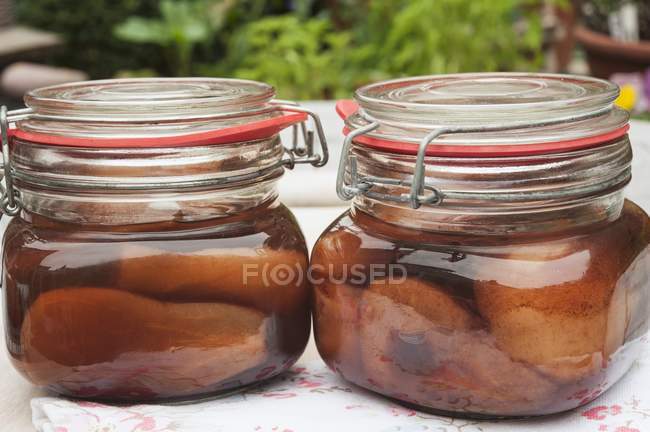 Vista de cerca de dos frascos de peras en brandy de cereza - foto de stock