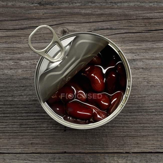 An opened tin of kidney beans over wooden surface — Stock Photo