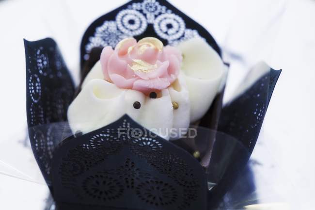 Vue rapprochée de praliné élégant décoré de rose dans un étui en papier noir — Photo de stock