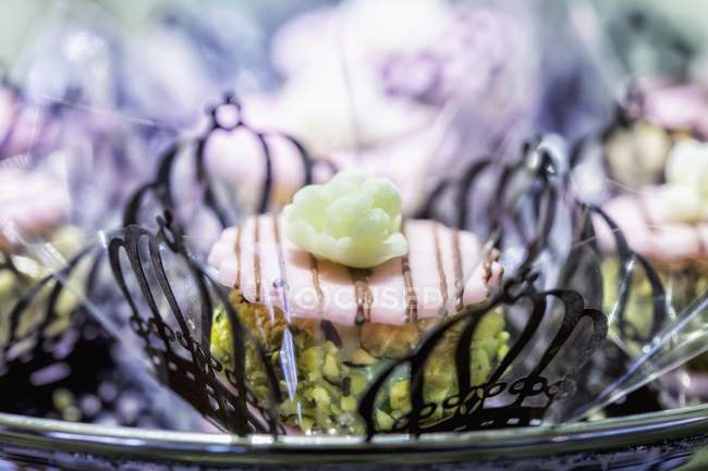 Close-up vista de produtos de confeitaria pistache com flores de açúcar em casos de papel filligree — Fotografia de Stock