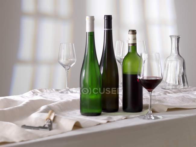 Glass of red wine with bottles — Stock Photo