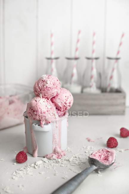 Vista de primer plano de yogur de frambuesa congelado con chocolate blanco rallado en una olla - foto de stock