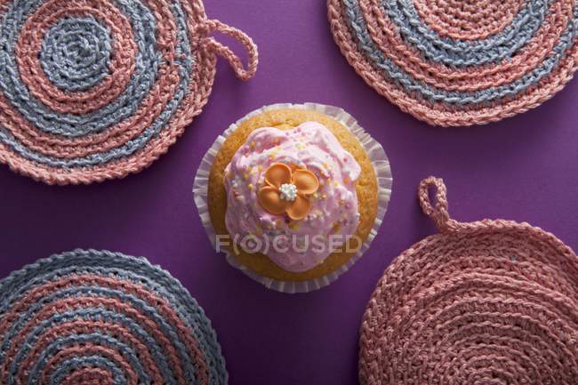 Flower cupcake between crocheted pot holders — Stock Photo