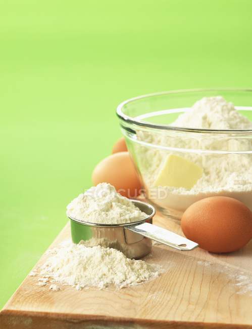 Vista de perto de farinha com manteiga e ovos em uma tábua de cortar — Fotografia de Stock