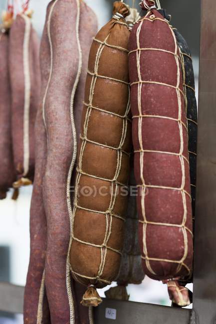 Vista close-up de vários tipos de salsichas de salame pendurado — Fotografia de Stock