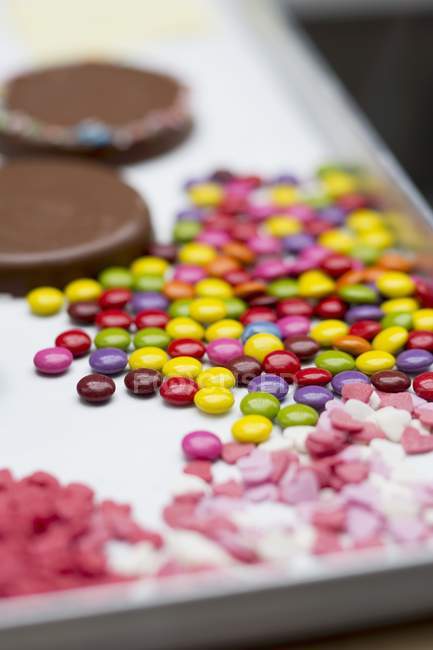 Vista de cerca de coloridos granos de chocolate y corazones de azúcar - foto de stock