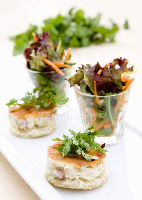 Closeup view of quiches served with mixed leaf salad — Stock Photo