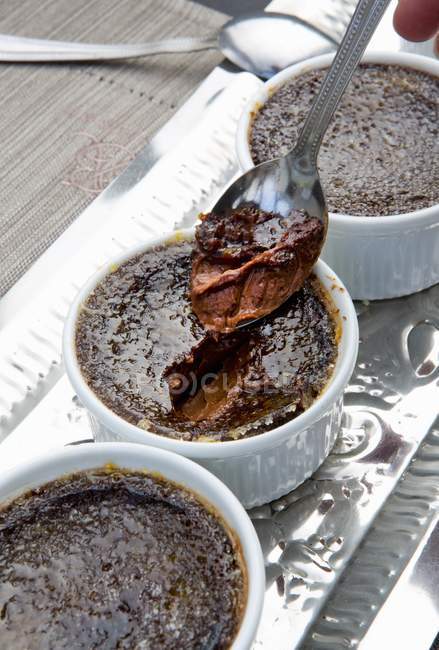 Vue rapprochée de chocolat crème brulée sur cuillère et dans des bols — Photo de stock