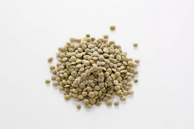 Vista de close-up de lentilhas verdes em heap na superfície branca — Fotografia de Stock